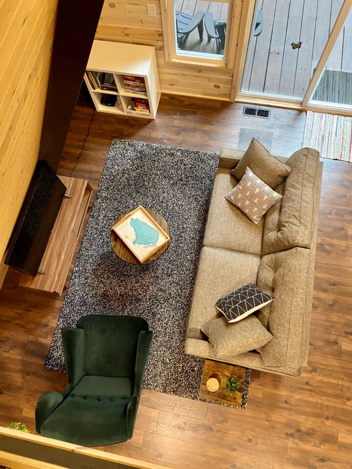 view from loft looking down at green chair and tan sofa in living room of a-frame