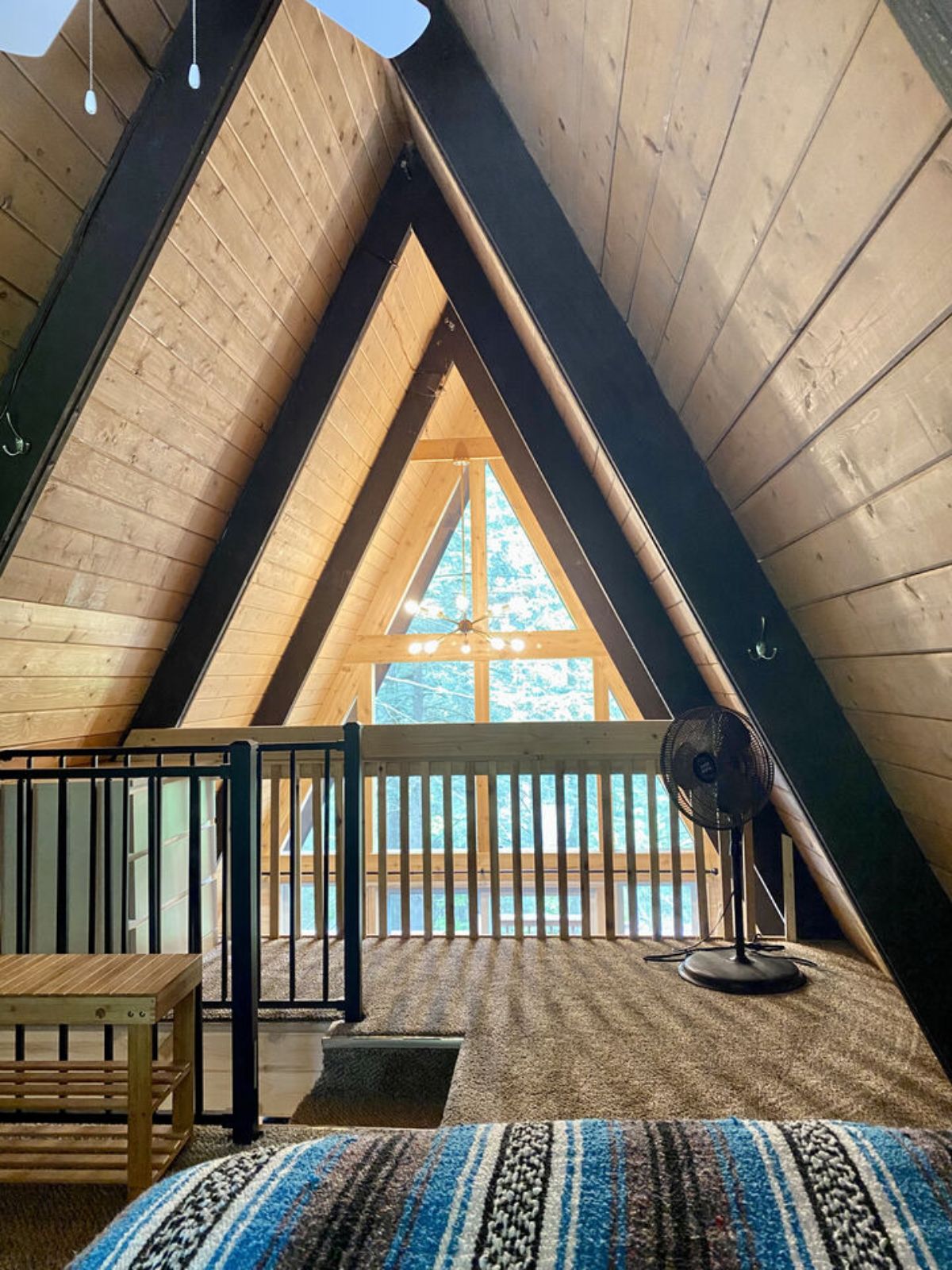 view across loft in a-frame with black railing at edge of loft