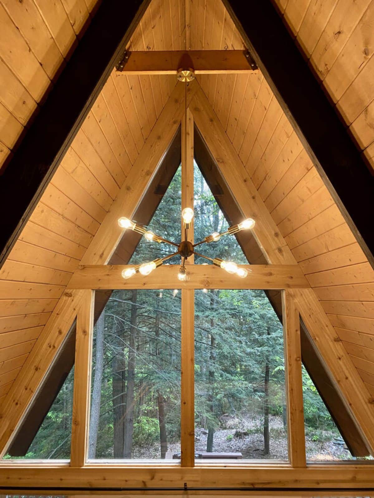 view of wall of windows and edison bulb chandelier in a-frame