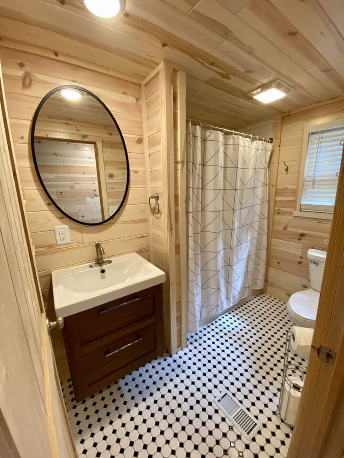 round mirror above white counter vanity in bathroom with tile floor