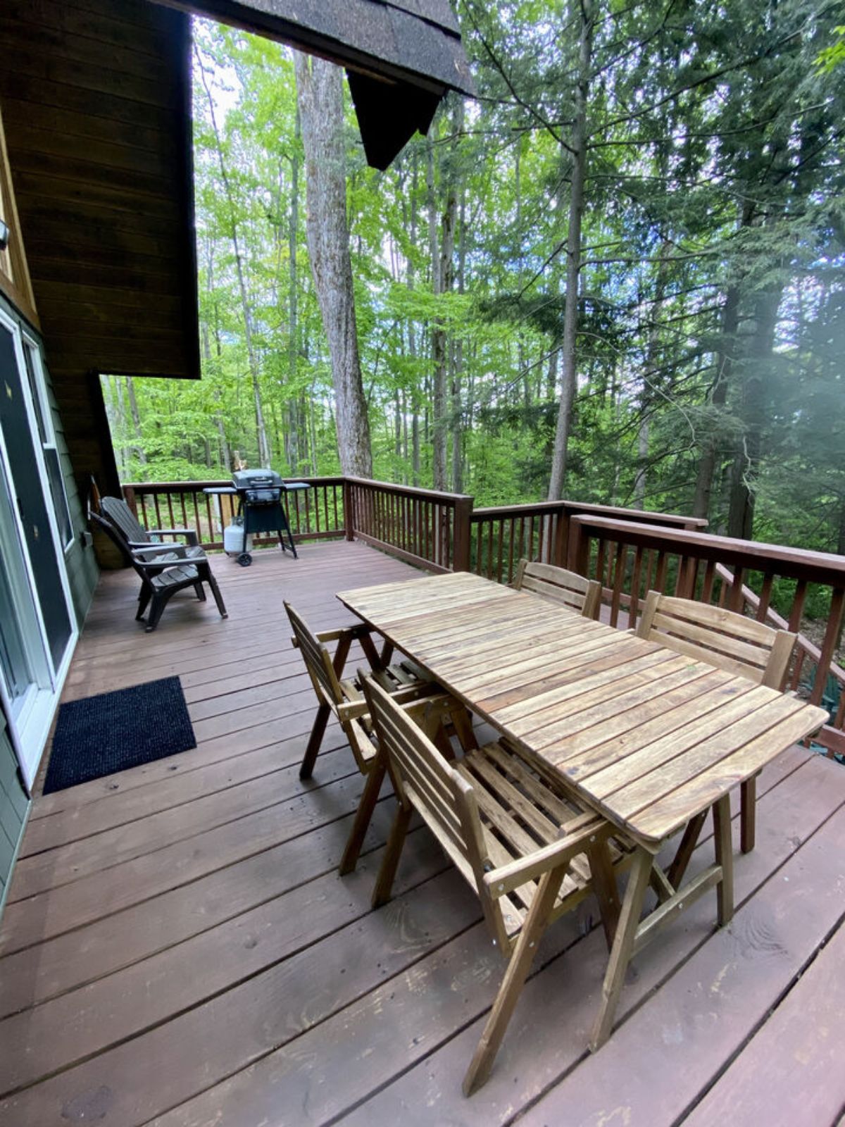 a-frame cabin deck with wood table and chairs and grill
