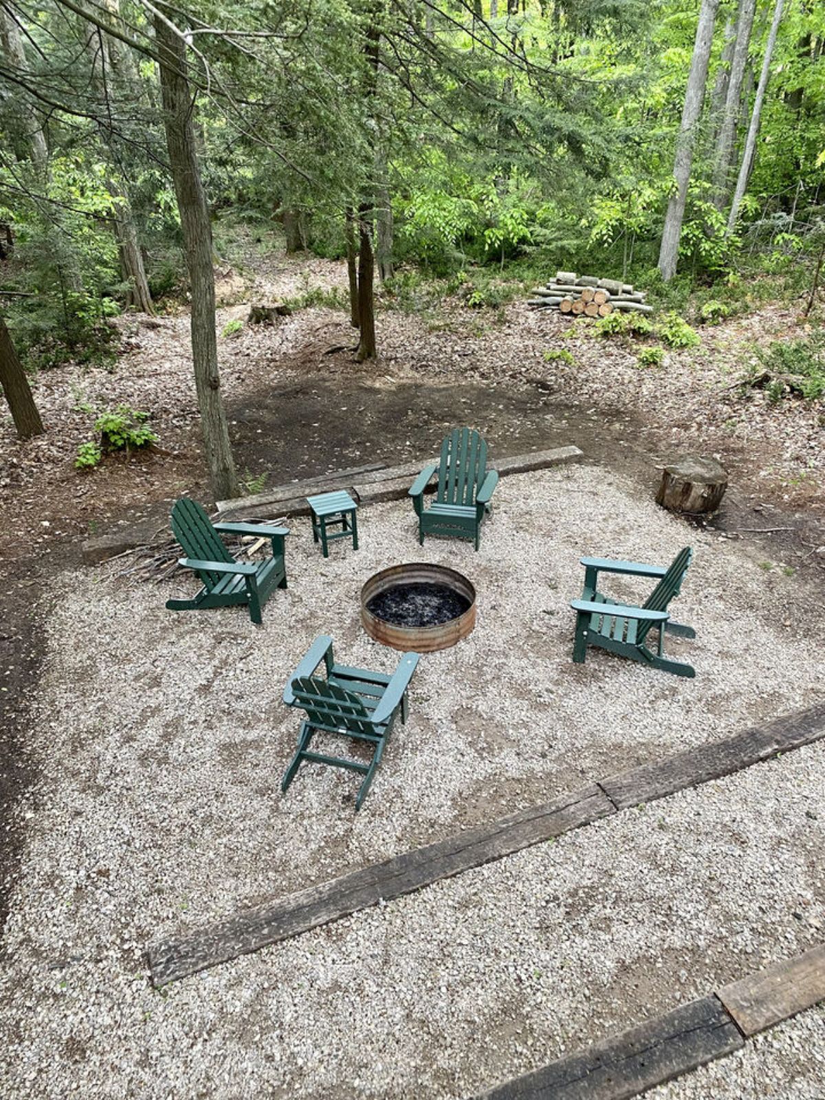 firepit outside cabin with green chairs