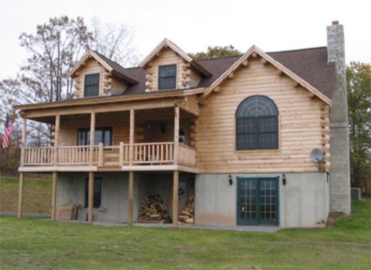 back of cabin from outside showing patio, deck, and two dormer windows