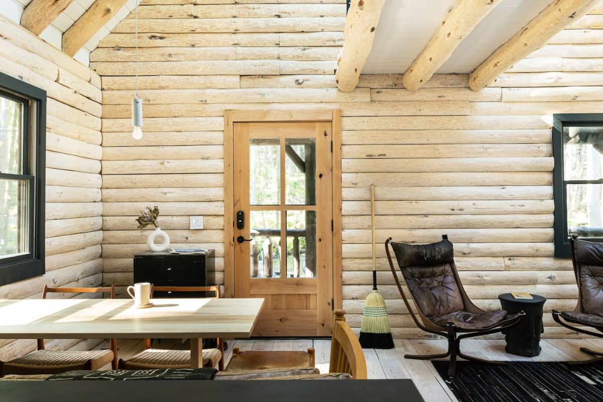 desk and chair inside log cabin space with glass window on door