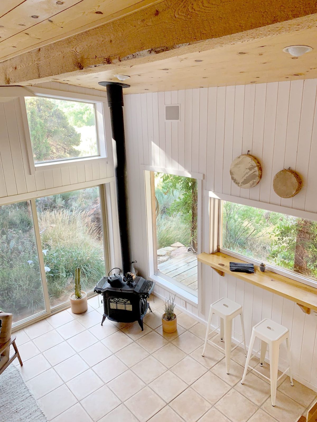 living room with black wood stove in corner near wall of picture windows and window seat