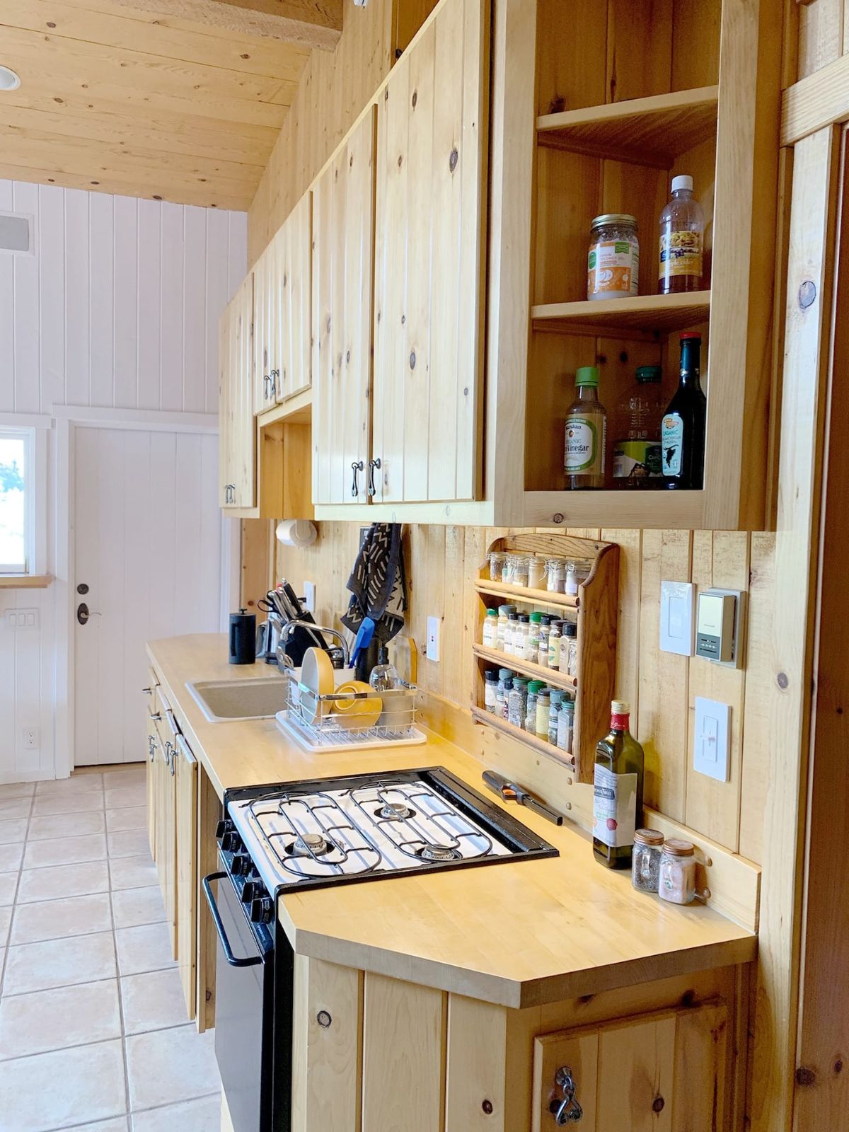 view across light wood cabinets in kitchen with stovetop inset in center