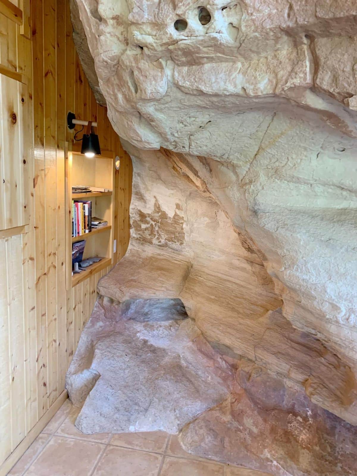 rock wall inside cabin with nook in corner and lamp against wall
