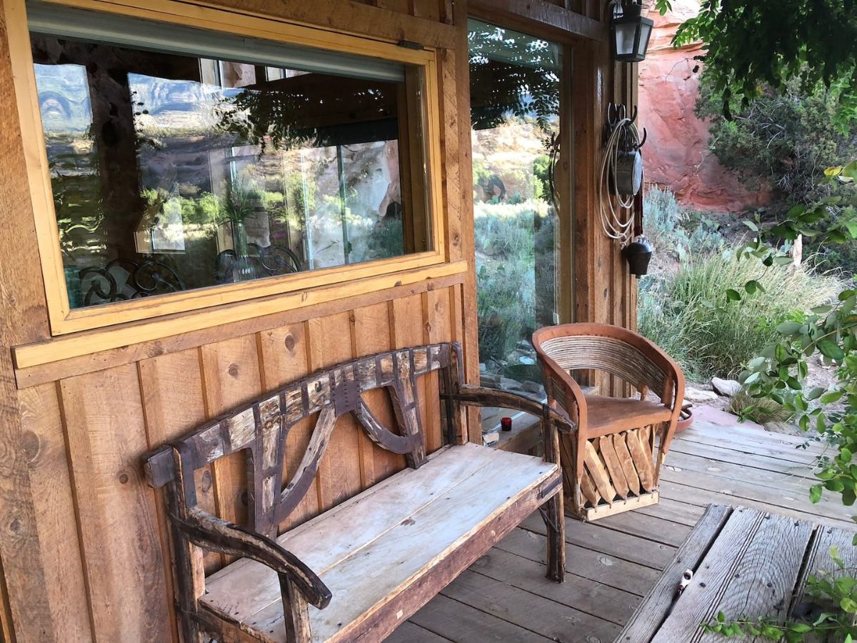 wicker bench with white cushion next to chair on porch