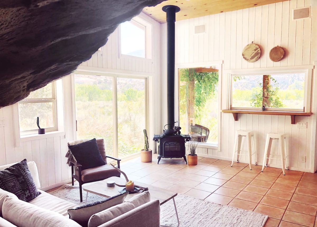 view across open living room with sofa on left foreground and wood stove in background