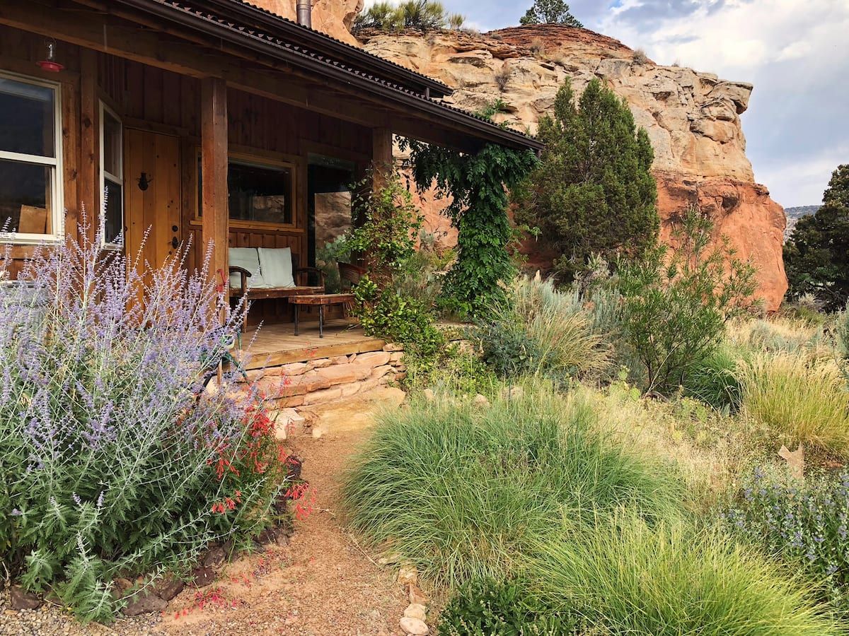 cabin against rock outcropping with dessert shrubs in front of porch