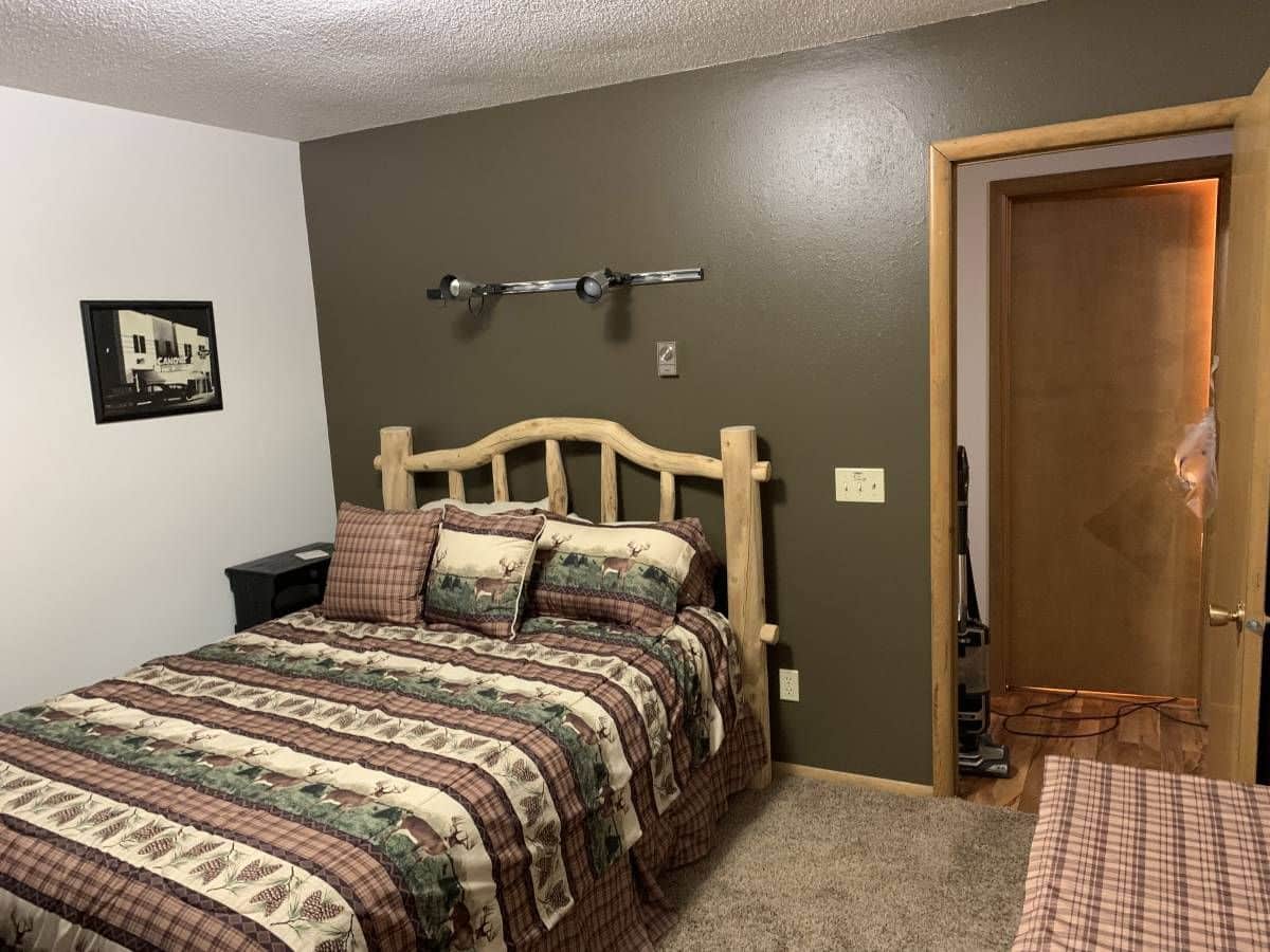 green wall against white wall in bedroom with wood bed and striped bedding