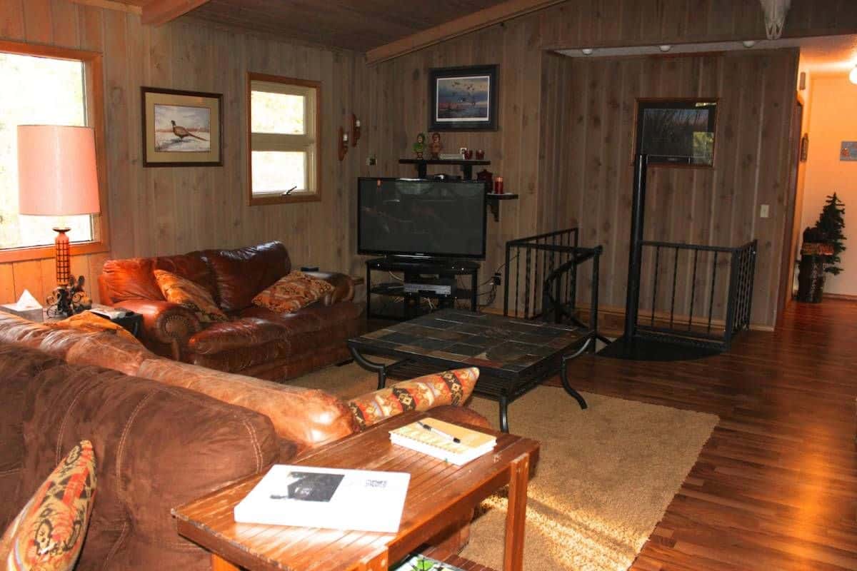 sofa in foreground with tv in background and stairs behind tv