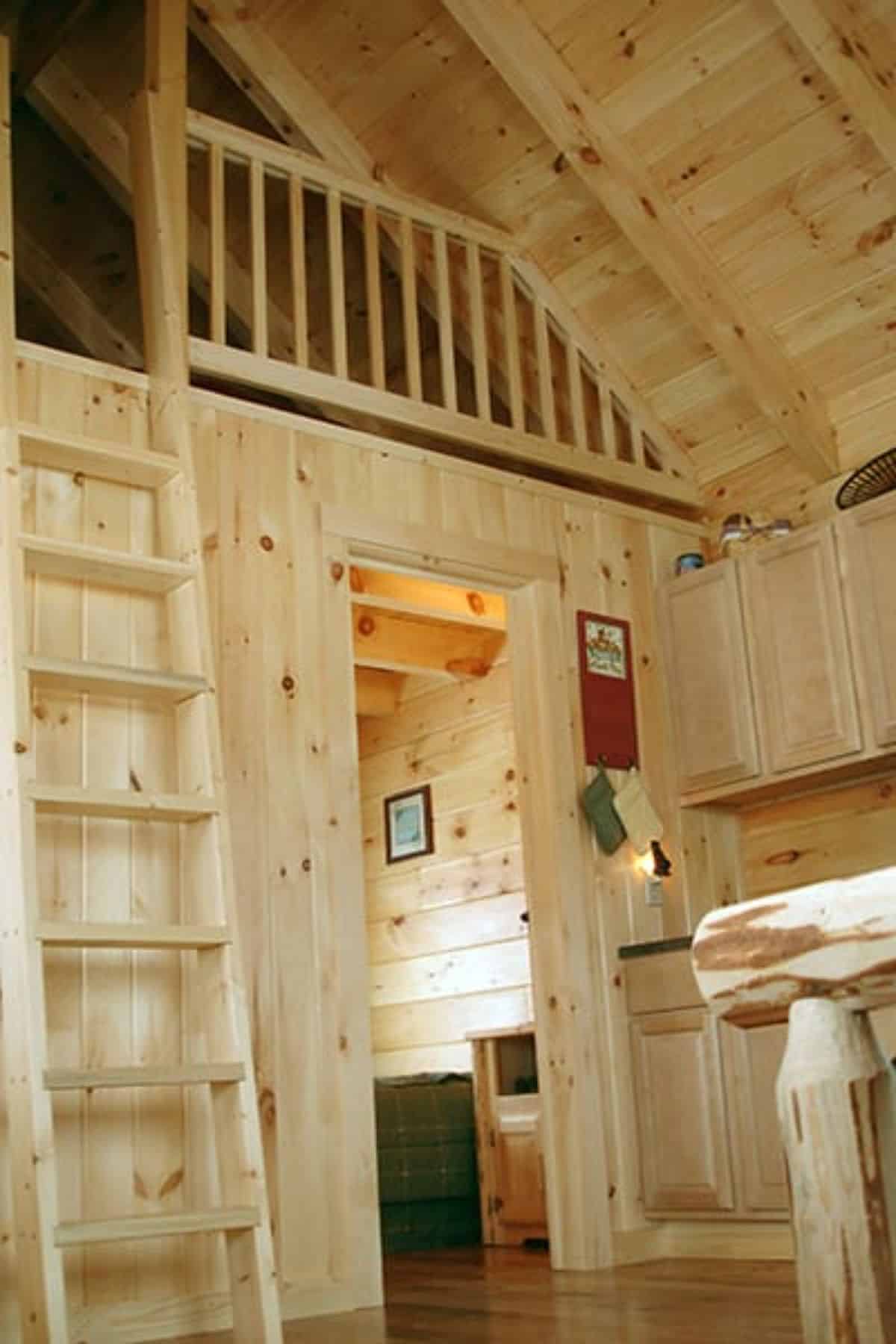 ladder to loft on left, door to bedroom in background, and kitchen counters on right