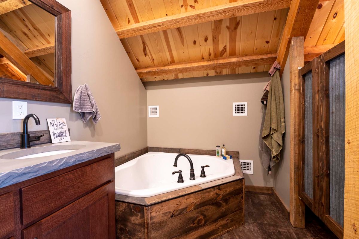 white soaking tub with wood surround in corner of bathroom