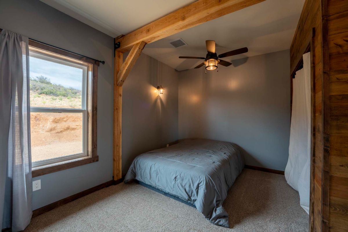 gray room with bed against wall and exposed beam ceiling