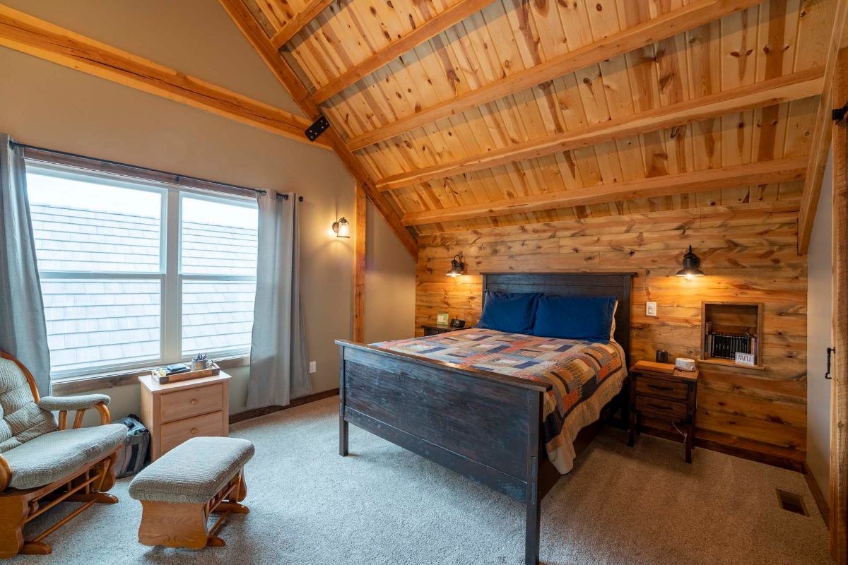 wood bed frame against loft ceiling with window to the left