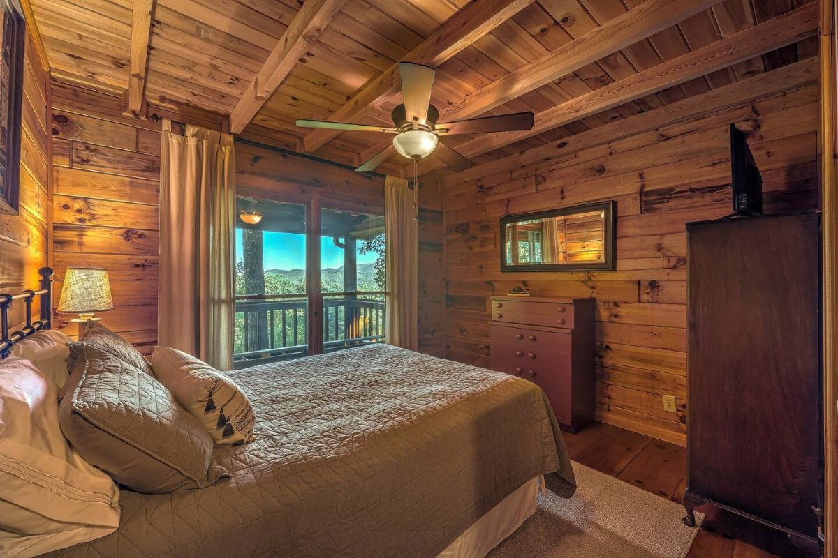 chest of drawers against wood wall across from queen bed