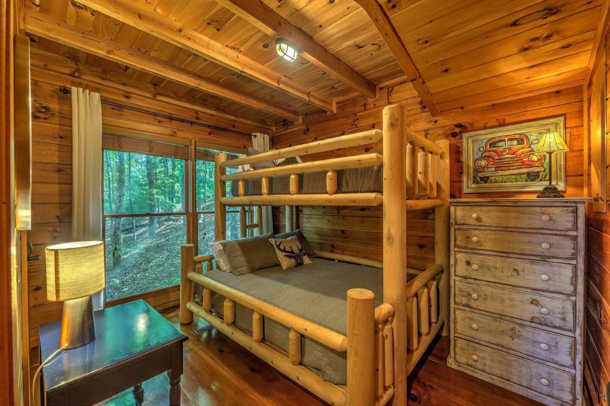 wood frame bunk beds next to picture window in bedroom