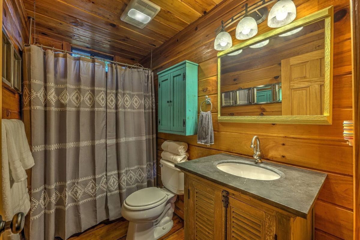 striped shower curtain next to teal over toilet storage