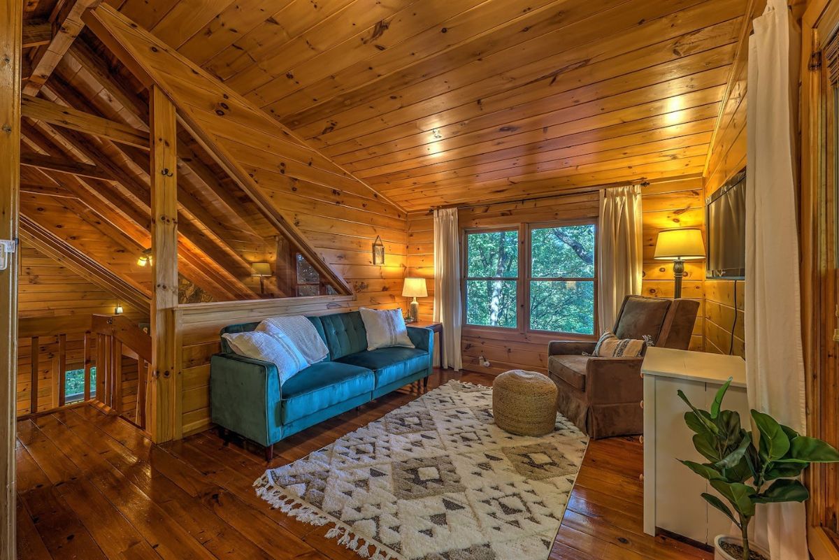 teal sofa against railing in loft with picture window to right