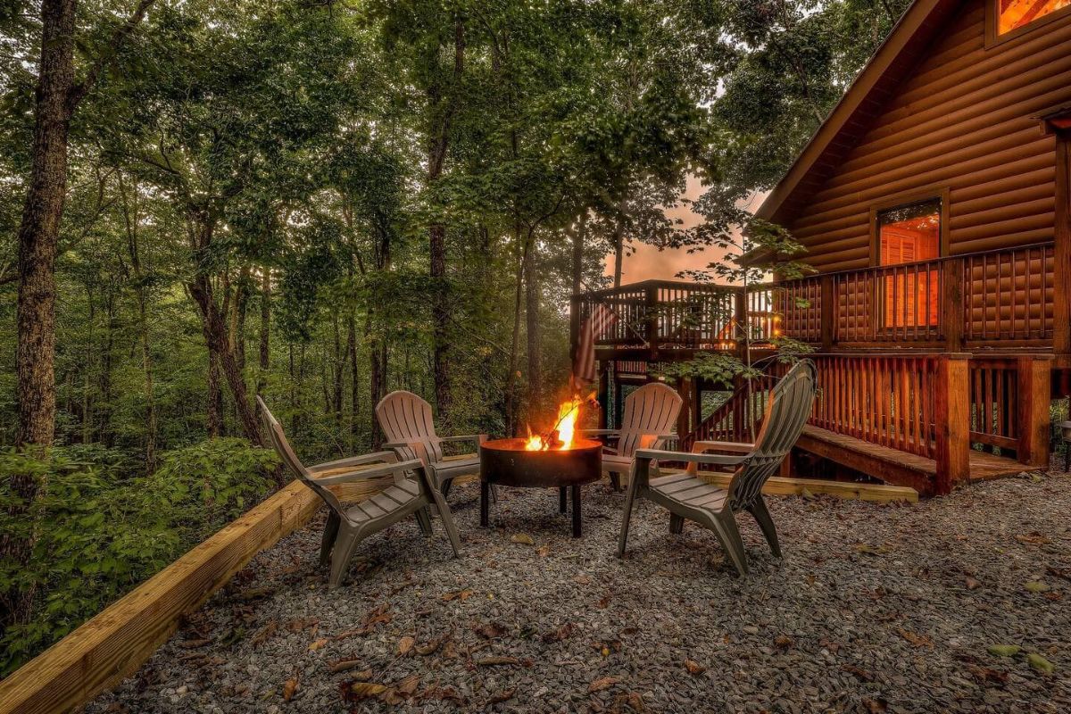 chairs around fire pit in front of cabin on hill