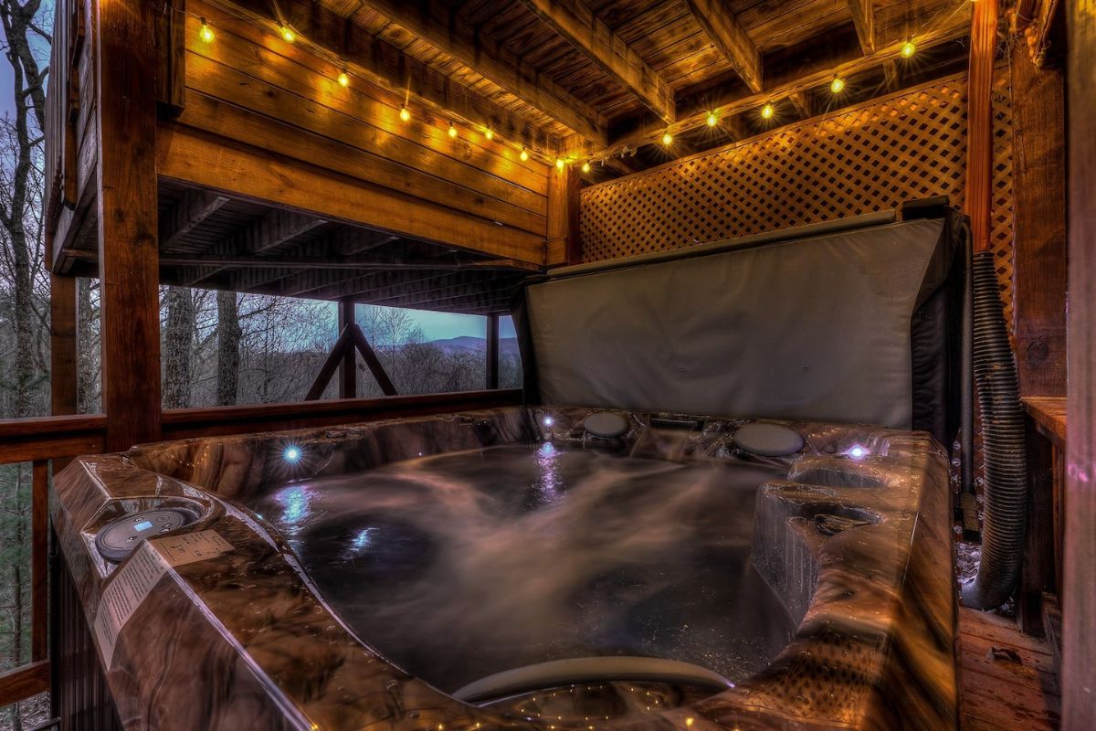 hot tub under deck with twinkle lights around edge of roof
