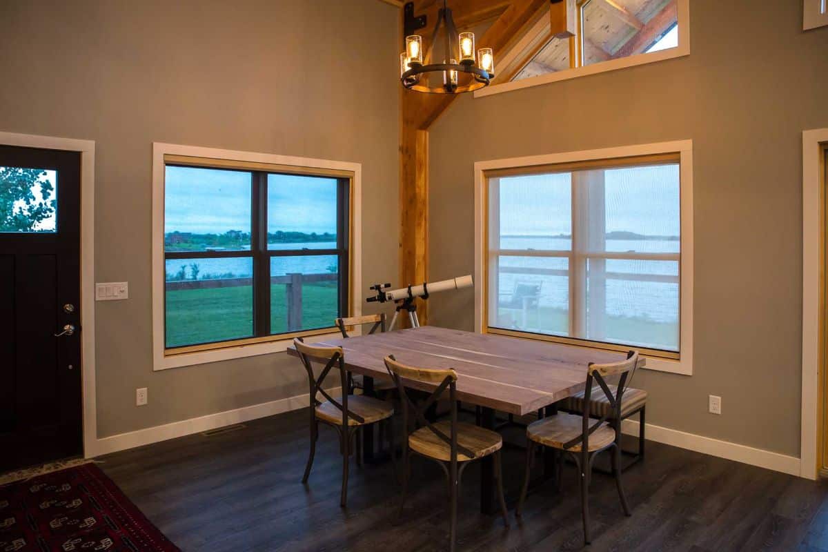 wood dining table by picture windows overlooking water