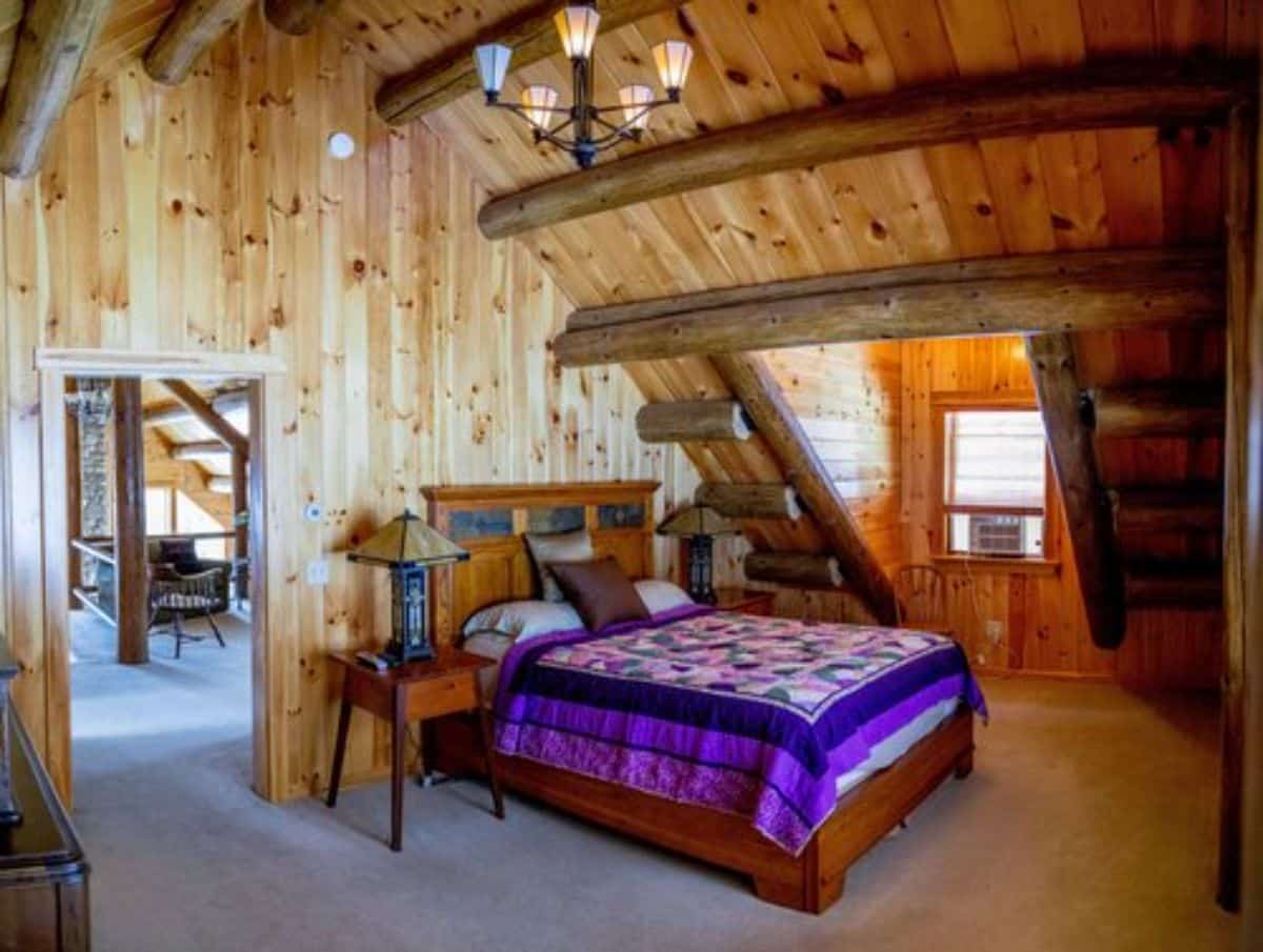 loft bedroom with wood frame bed against wall by window