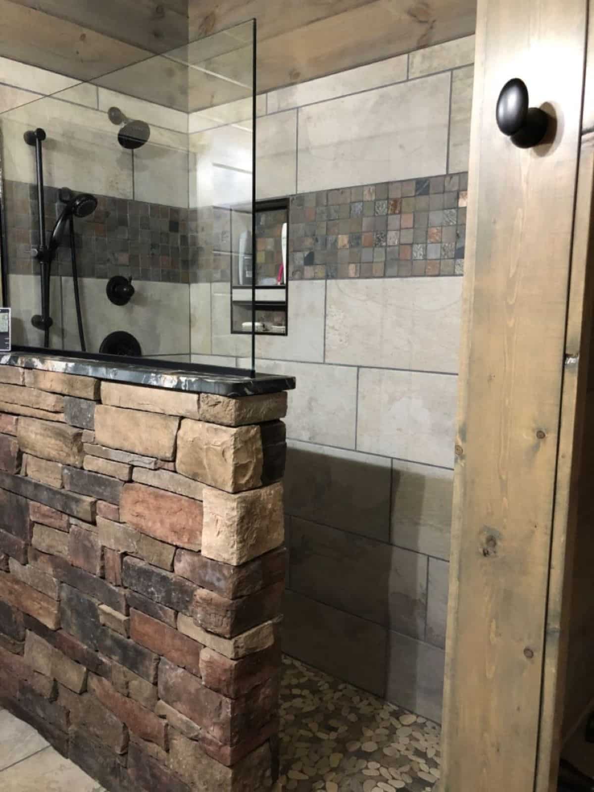 tiled shower with brick wall on outside