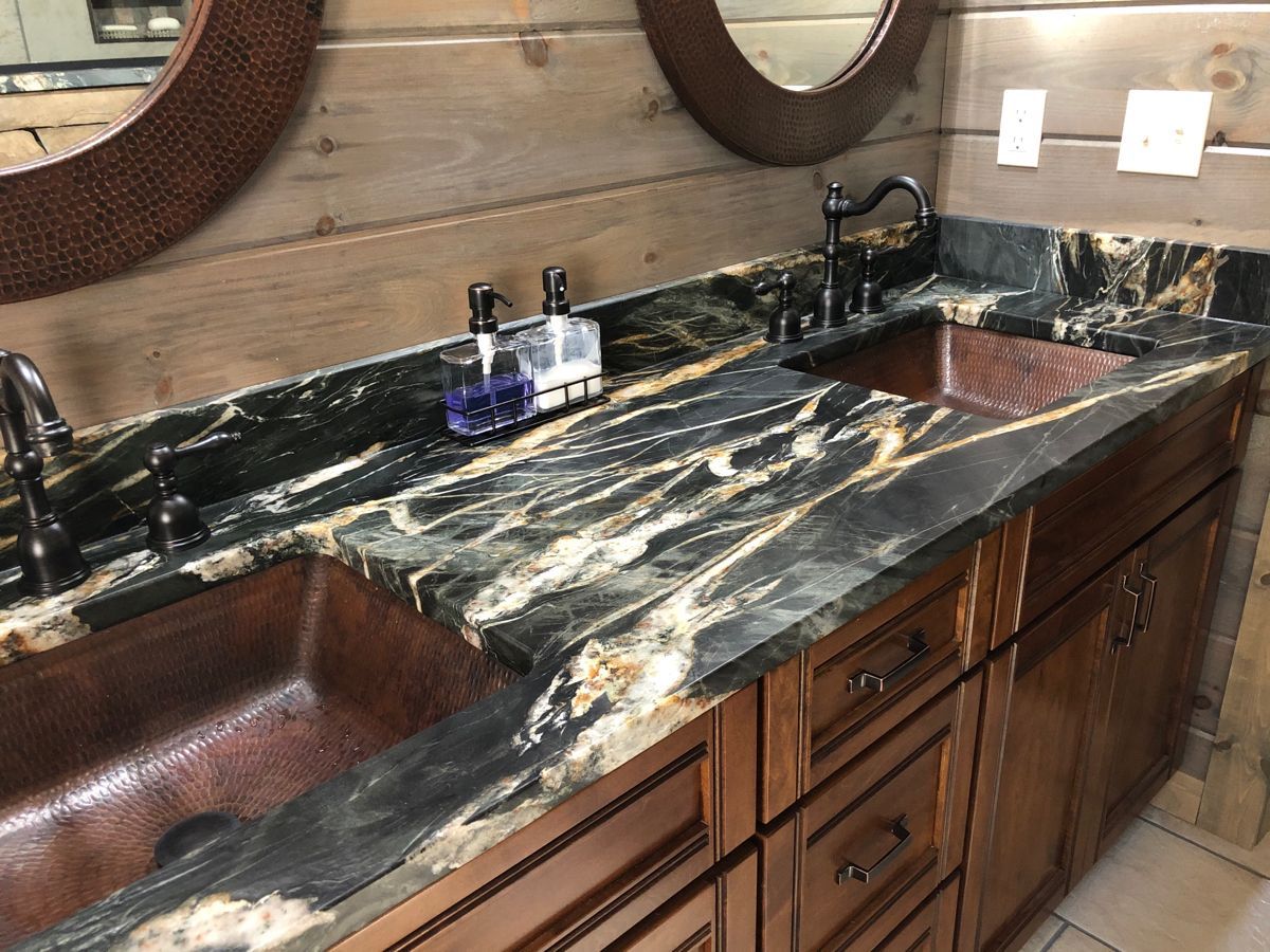 two copper sinks in bathroom below oval mirrors