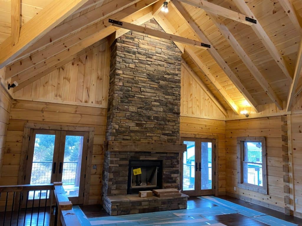 stone fireplace against wall between picture windows