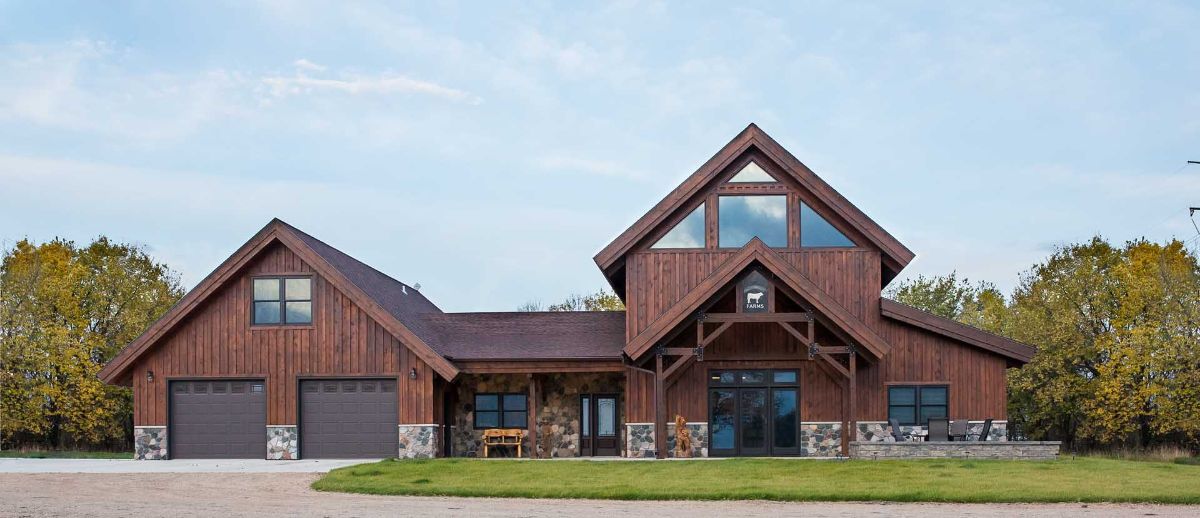 front of brown cabin with stone accents and concrete drive on left