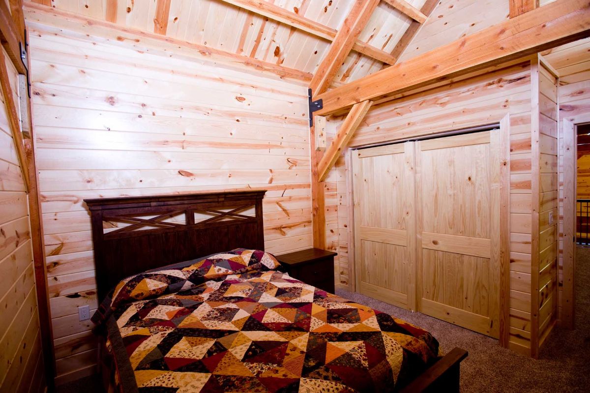 bed against light wood wall with quilt