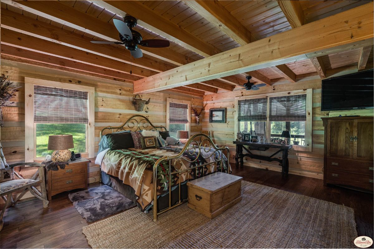 master bedroom in cabin with windows on both sides and ceiling fan above bed