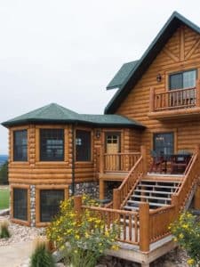 side of log cabin with green roof and gazebo on side